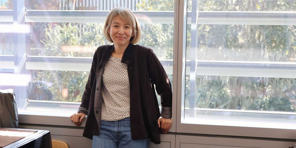 Portray of Gloria Kim, Ph.D. standing in front of the window in her office.