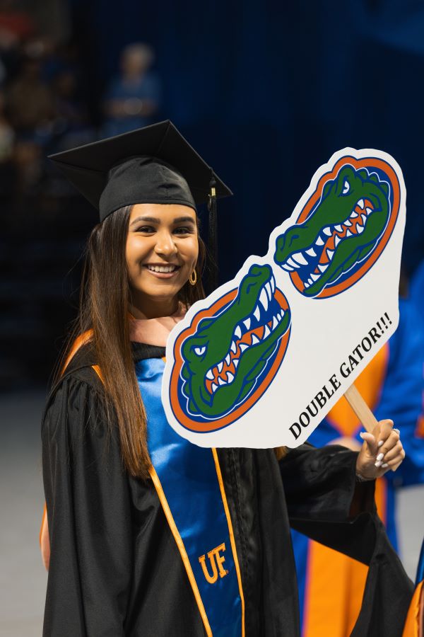 Photo of a female University of Florida graduate holding a sign with two gator heads that reads "Double Gator!!!"