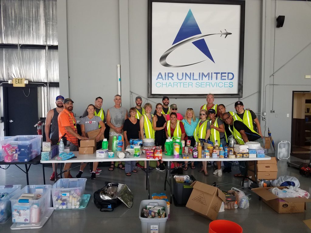 Volunteers behind a table of donated items at Air Unlimited warehouse.