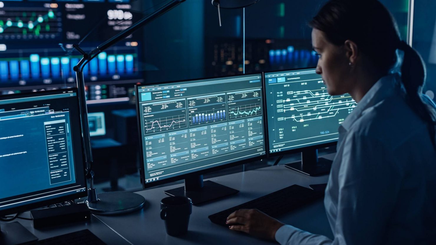 Photo of a woman looking at cybersecurity data on multiple computer monitors (credit: Shutterstock)