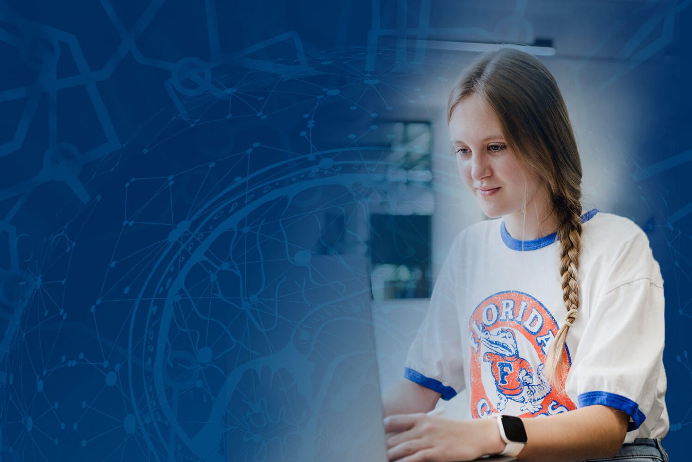 A female student in a UF T-shirt works at a laptop, superimposed over stylized graphics of a human brain, binary code, and electronic circuits.