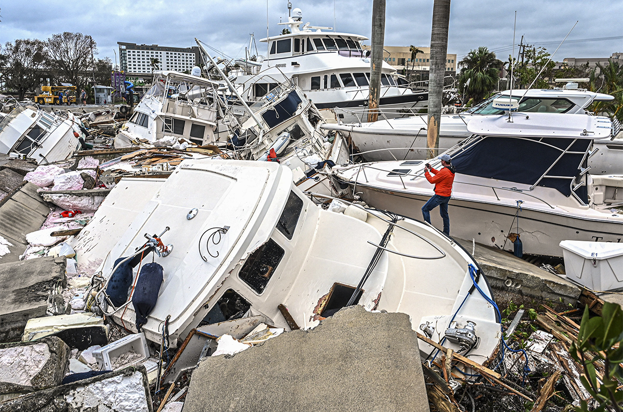 TOPSHOT - A man takes photos of boats damaged by Hurricane Ian in Fort Myers, Florida, on September 29, 2022. - Hurricane Ian left much of coastal southwest Florida in darkness early on Thursday, bringing "catastrophic" flooding that left officials readying a huge emergency response to a storm of rare intensity. The National Hurricane Center said the eye of the "extremely dangerous" hurricane made landfall just after 3:00 pm (1900 GMT) on the barrier island of Cayo Costa, west of the city of Fort Myers. (Photo by Giorgio VIERA / AFP) (Photo by GIORGIO VIERA/AFP via Getty Images)