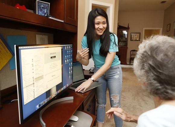 Ming Yang helps a senior citizen with her computer.