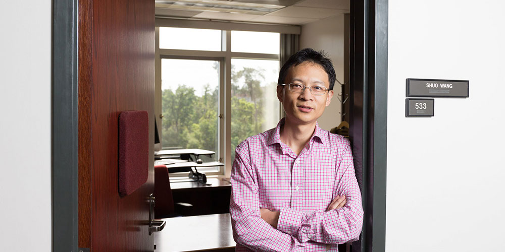 Shuo Wang, Ph.D., standing in the doorway to his office.