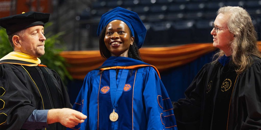 A Ph.D. graduate is hooded during UF's doctoral commencement ceremony.
