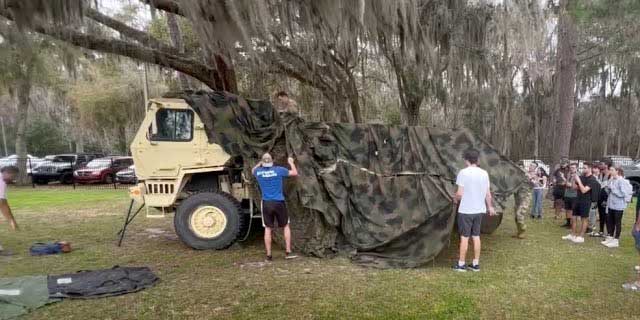 Mechanical engineering students at UF deploy a device they designed to allow soldiers to quickly camouflage military vehicles.