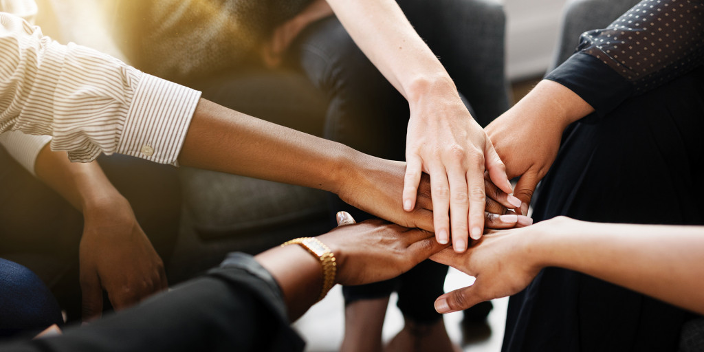 Diverse group of business people's hands showing unity and teamwork. Business people's hands of different ethnicity coming together in a display of teamwork and unity. Diverse hands for teamwork