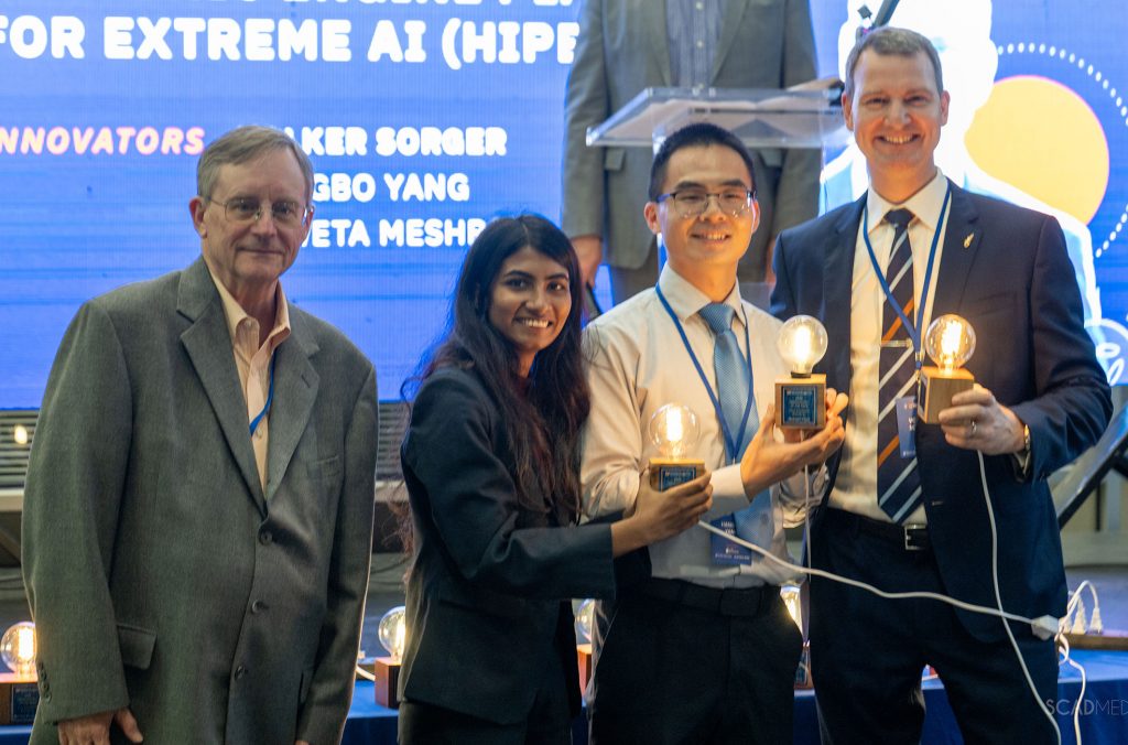 Volker Sorger, Ph.D, the Walden and Paula Rhines Endowed Professor in Semiconductor Photonics and deputy director of Strategic Initiatives at the Florida Semiconductor Institute, and his research team, Hangbo Yang, Ph.D., a research associate professor, and Shweta Meshram, a graduate student in the Department of Electrical and Computer Engineering receive their award from Rick Croley(on left) for transforming data communication within high-performance computing systems.