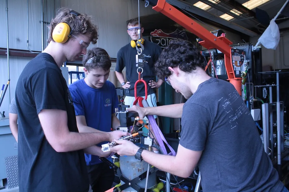 From left: Peter Chandler, Miles Moerman, Luke Needham and Austin Martin using a small crane to position a test tank while preparing for an injector cold flow test as part of the team’s liquid rocket development process.