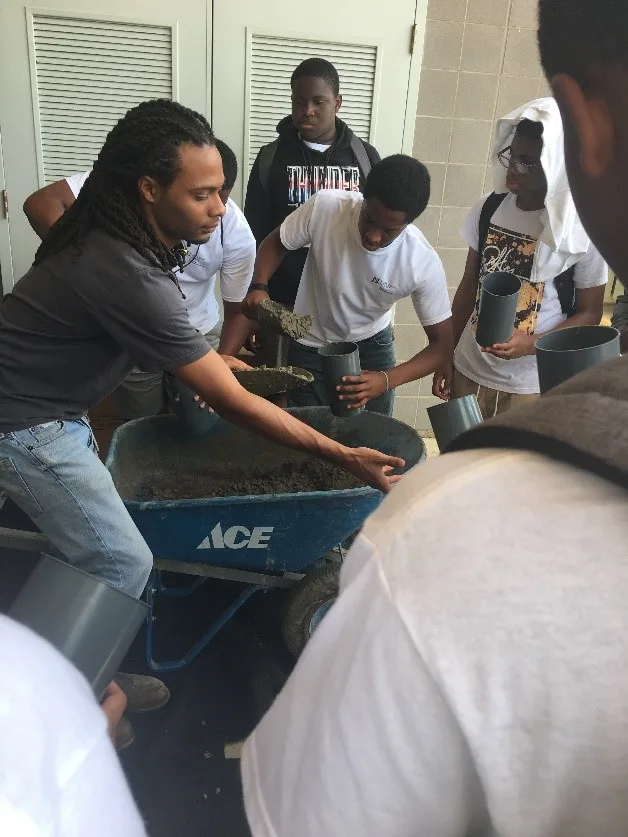 A laboratory event where a lab tech is showing kids how to mix cement.