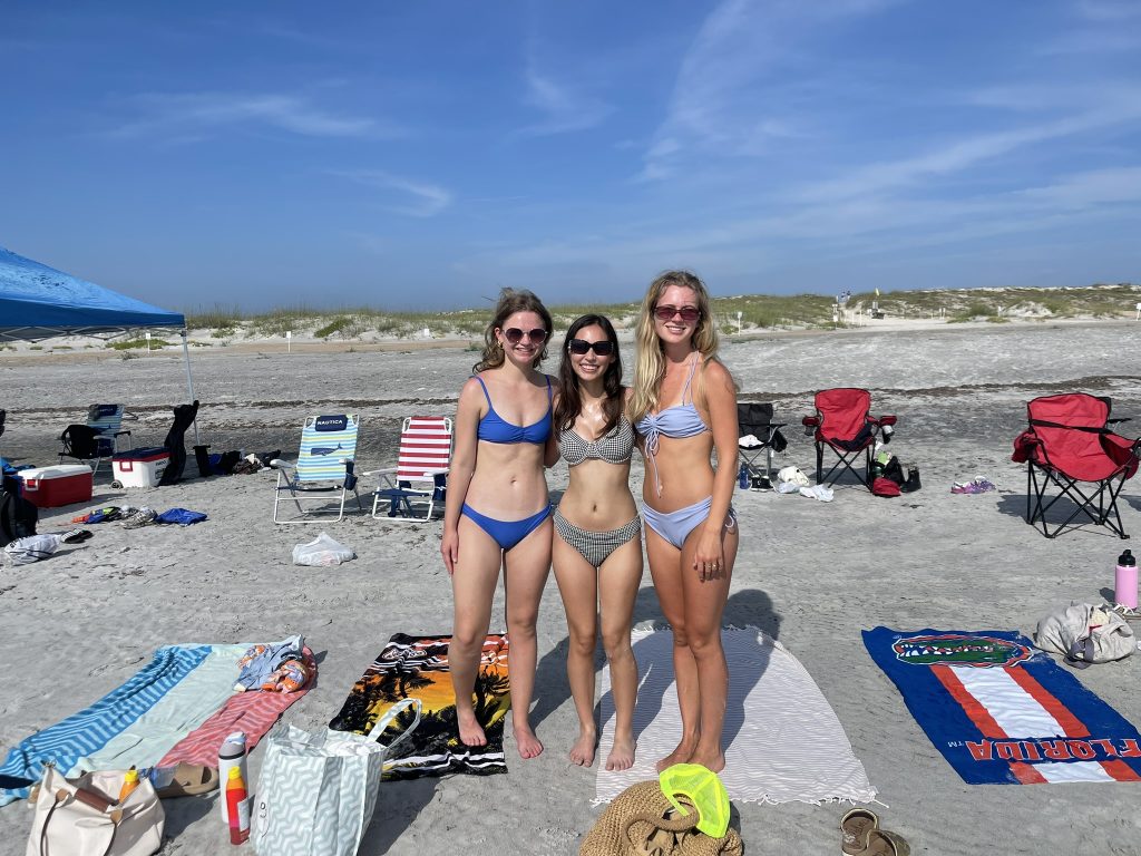 A trio of female students pose together on the beach. 