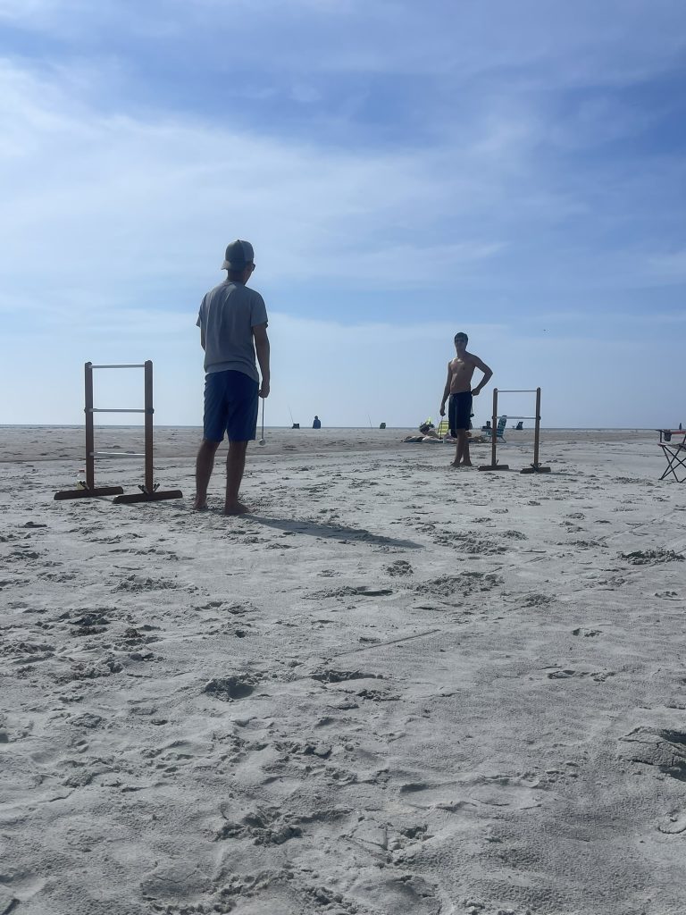 Two male students waiting their turn during ladder golf.