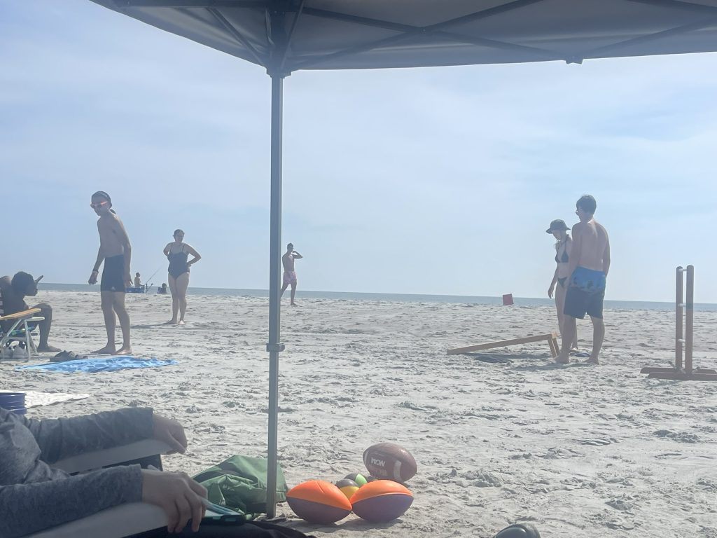 Cornhole partner's watching the other team make a play. 