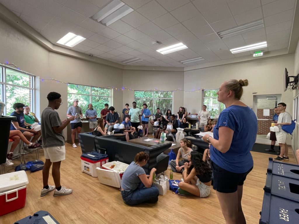 A staff member talking to a lobby full of students. 
