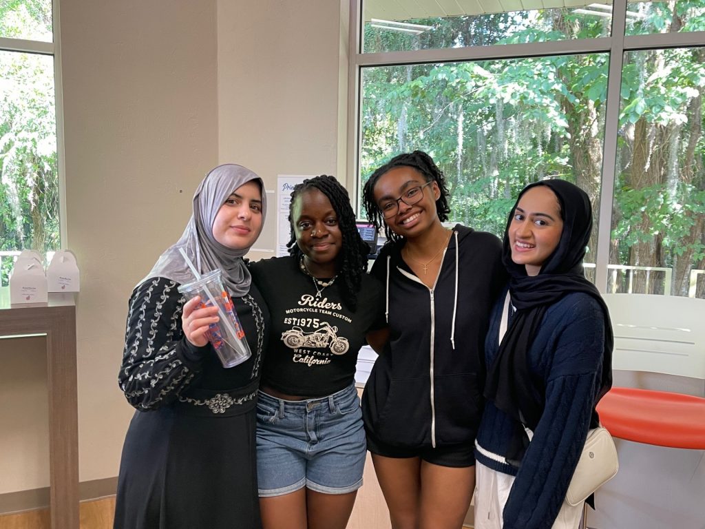 A group of students posing for a photo, one is holding a cup. 