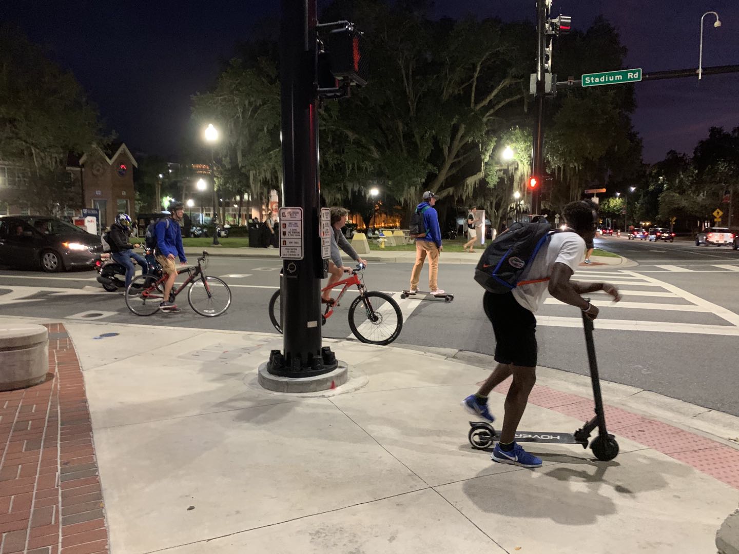 Students use bikes and scooters on UF campus at night