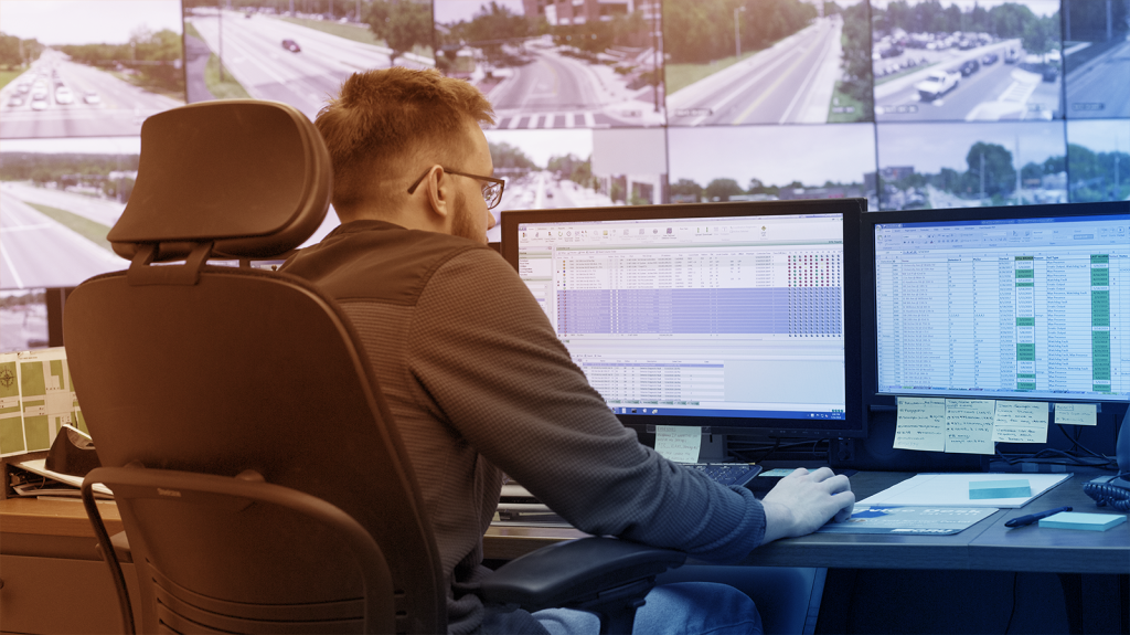 Man looks at computer screen with screens displaying streets in the background.